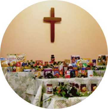 Circular image showing a cross in the background and a set of tables in the foreground with food items on them.
