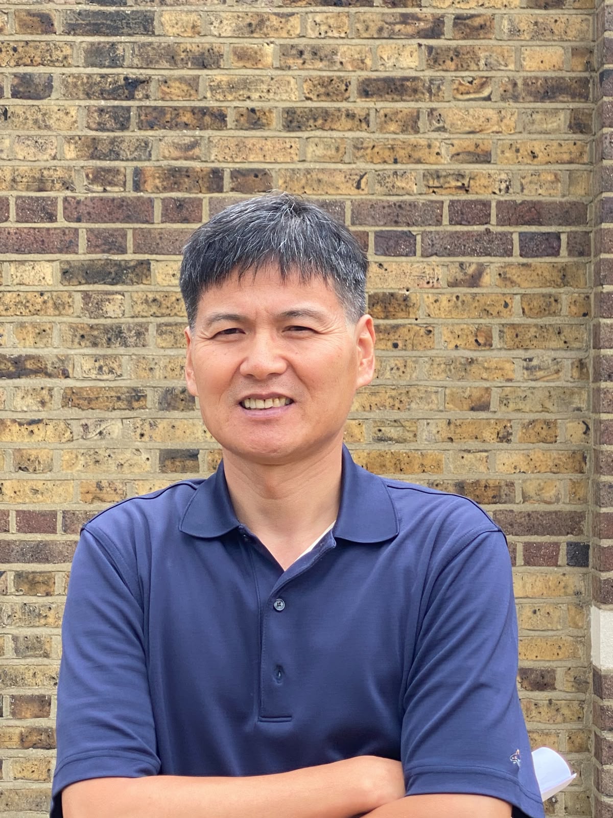 A picture of Soon smiling at the camera in a dark blue shirt.